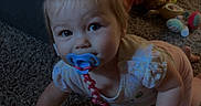 Ellie is registered to the contest to win money with this photo: baby, child, crawling, pacifier, carpet, indoor, home, blanket, toys, playroom, infant, portrait, blue_eyes, blonde_hair, sitting, floor, couch, clothing, smiling, baby_toy
