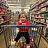 Ellie joined the competition — help win amazing prizes! child, toddler, baby, smiling, happy, grocery_store, shopping_cart, supermarket, aisle, food, sauces, snacks, yogurt, red_shirt, black_pants, shoes, portrait, indoors, shopping, shelves