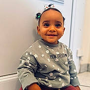 Siyanna participe au concours pour gagner de l'argent avec cette photo : baby, bright_eyes, casual_clothing, child, cute, floor, floral_pattern, hair_accessories, happy, indoor, pants, person, playful, portrait, sitting, small_earrings, smiling, sweatshirt, toddler, young_child