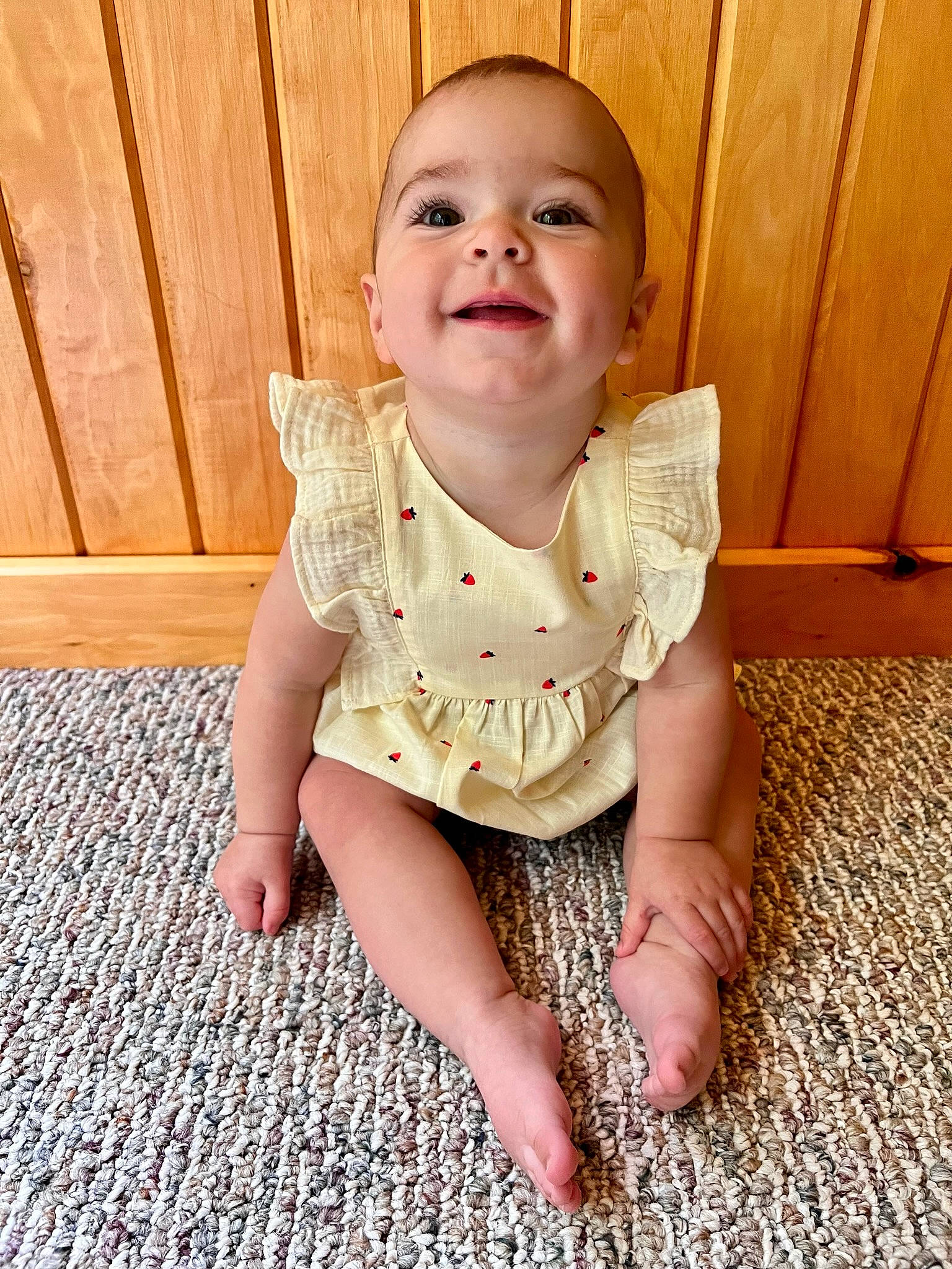 Caroline is registered to the contest to win money with this photo: arm, baby_toddler_clothing, cheek, clothing, dress, eye, face, fawn, finger, floor, flooring, hand, iris, joy, leg, neck, person, skin, sleeve, smile