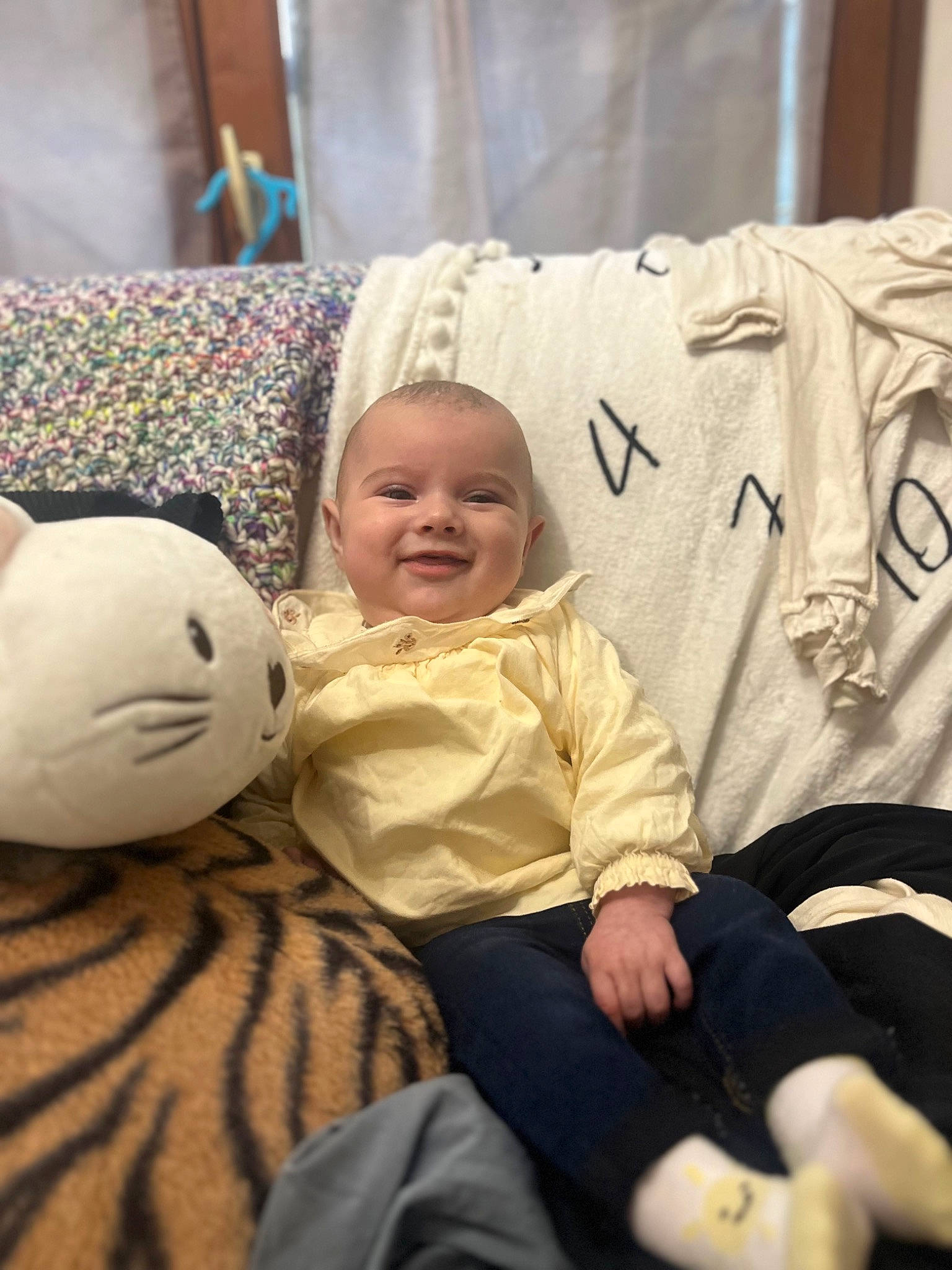 Angelina a rejoint le concours — aidez-le/la à gagner de superbes lots ! baby, child, comfort, event, facial_expression, flooring, fun, happy, human, joy, lap, linens, mammal, person, pillow, room, sitting, skin, smile, t_shirt