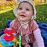 Rose a rejoint le concours — aidez-le/la à gagner de superbes lots ! baby, infant, child, outdoor, grass, toy, colorful_toy, bonnet, pink_clothing, blanket, smiling, happy, playing, sunlight, nature, cute, portrait, sitting, hands, feet