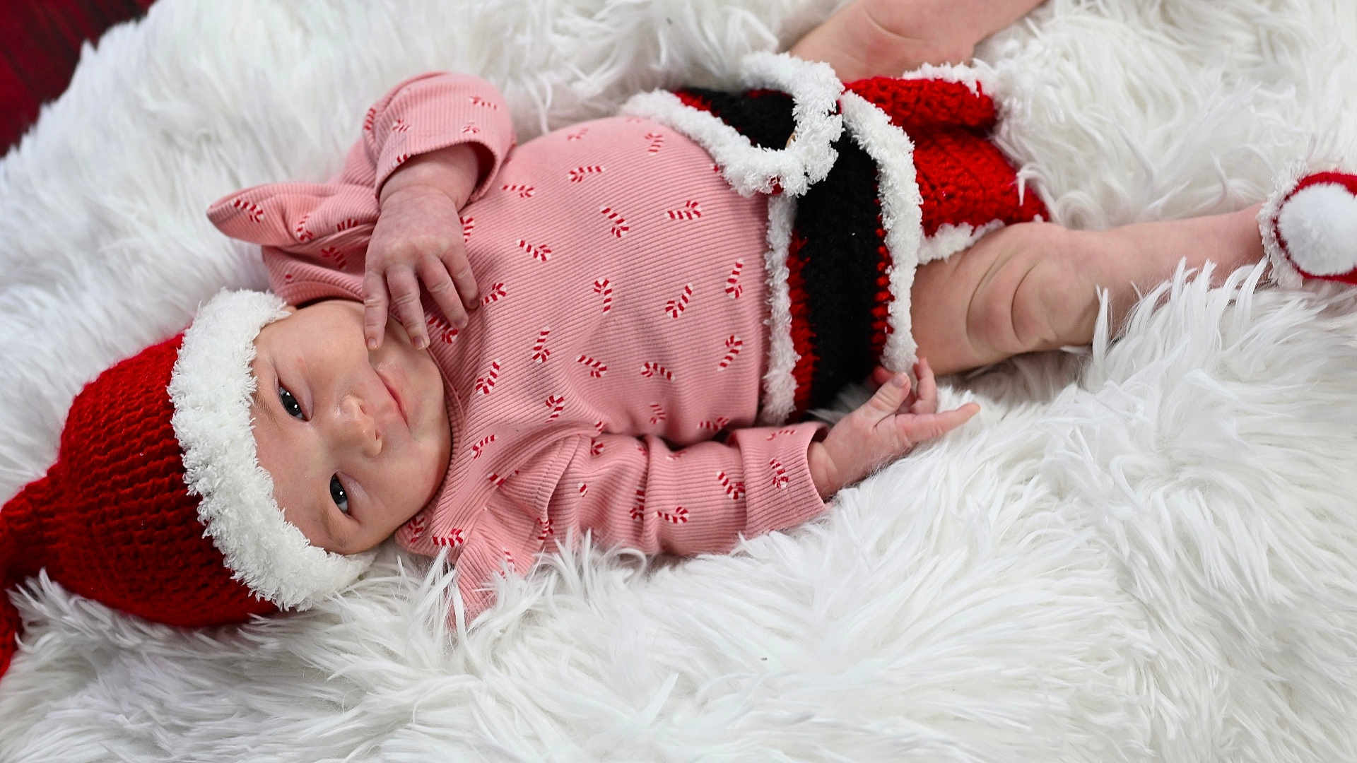 Elizabeth is registered to the contest to win money with this photo: baby, infant, christmas, holiday, red_hat, knitwear, blanket, white_fur, cute, festive, sleepwear, newborn, child, lying_down, cozy, cute_expression, hand, foot, portrait, indoors