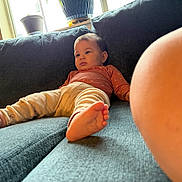 Elizabeth is registered to the contest to win money with this photo: baby, child, couch, sofa, relaxed, indoor, window, potted_plant, foot, skin, clothing, pants, long_sleeve, expression, curious, texture, cozy, home, pregnant_belly, casual