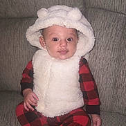 Yumi is registered to the contest to win money with this photo: baby, child, hood, fluffy, vest, red_checkered_pajamas, couch, seated, indoor, cute, smiling, face, ears, cozy, clothing, person, infant, plush, comfortable, portrait