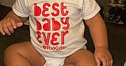Emoni joined the competition — help win amazing prizes! toddler, baby, child, sitting, shirt, bottle, floor, indoors, expressionless, hair_bow, clothing, footwear, furniture, shelf, shoes, person, portrait, snapchat, text_overlay, diaper