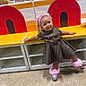 Emoni is registered to the contest to win money with this photo: toddler, child, girl, dress, pink, shoes, hair_accessories, bench, indoor, play_area, floor, colorful, patterned_clothing, smiling, person, fashion, cute, playful, standing, furniture