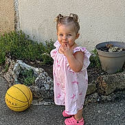 Giulia a rejoint le concours — aidez-le/la à gagner de superbes lots ! toddler, child, outdoor, dress, pink_shoes, basketball, pigtails, concrete, plants, flower_pot, smile, playful, garden, curly_hair, young_child, standing, casual, daylight, fun, candid