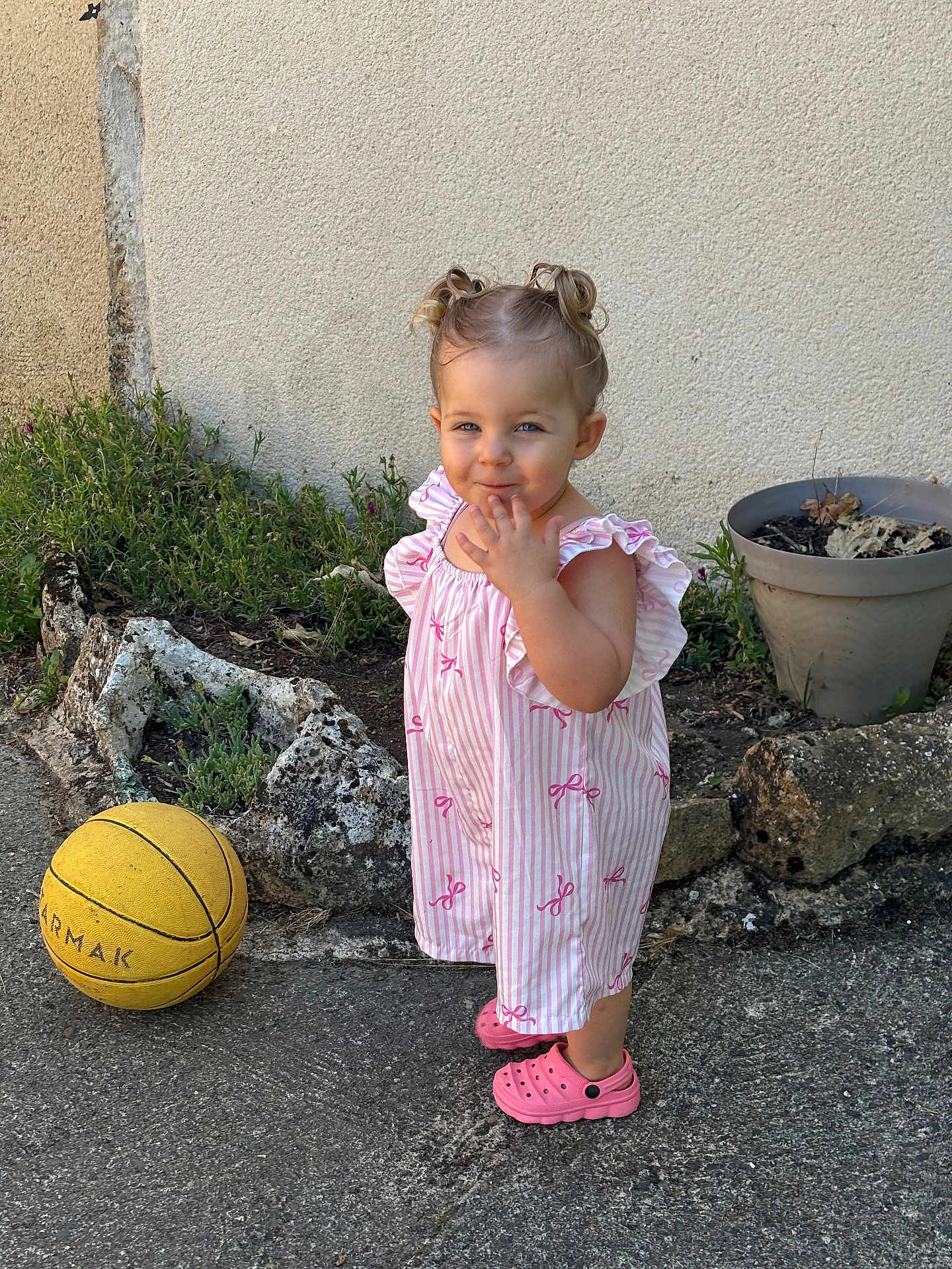 Giulia a rejoint le concours — aidez-le/la à gagner de superbes lots ! toddler, child, outdoor, dress, pink_shoes, basketball, pigtails, concrete, plants, flower_pot, smile, playful, garden, curly_hair, young_child, standing, casual, daylight, fun, candid