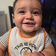 Matthew is registered to the contest to win money with this photo: baby, smiling, bib, face, child, indoor, cute, happy, person, portrait, closeup, clothing, infant, skin, hand, expression, sitting, young, cute_face, joy