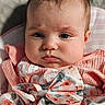 Emmie is registered to the contest to win money with this photo: baby, child, face, expression, pink_clothing, bow, floral_pattern, portrait, infant, cute, closeup, person, soft_texture, indoors, head, skin, young, sitting, apparel, happy