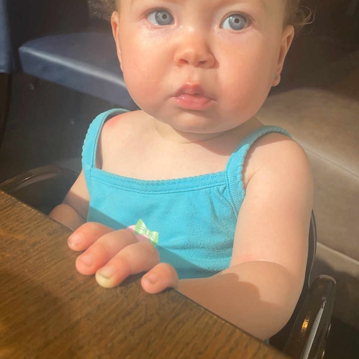 Moraya is registered to the contest to win money with this photo: toddler, child, baby, blue_eyes, curious_expression, sitting, table, wooden_table, sunlight, indoor, tank_top, clothing, skin, hair, face, hand, furniture, person, portrait, daylight