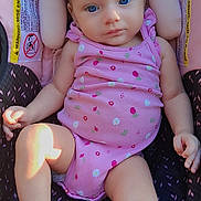 Remington is registered to the contest to win money with this photo: baby, infant, child, car_seat, pink_clothing, headband, bow, blue_eyes, onesie, warning_label, sitting, cute, soft_light, indoors, comfortable, portrait, skin, hand, foot, relax