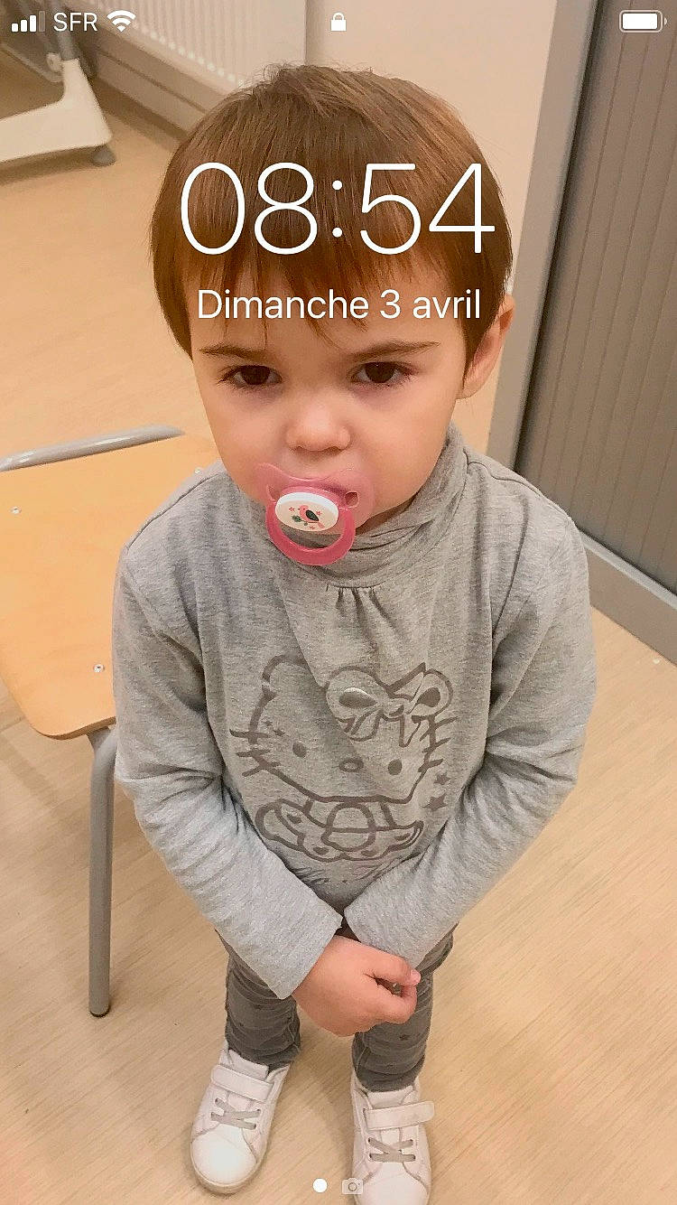Lya participe au concours pour gagner de l'argent avec cette photo : baby, baby_toddler_clothing, cheek, child, clothing, comfort, eyelash, floor, flooring, happy, head, headwear, lip, logo, nose, person, sitting, skin, sleeve, t_shirt