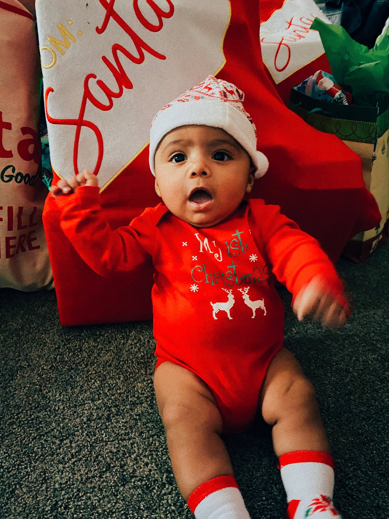 Kyng is registered to the contest to win money with this photo: baby, baby_toddler_clothing, cap, carmine, child, christmas, event, fictional_character, flooring, fun, happy, hat, headwear, holiday, human_leg, mammal, orange, person, red, sleeve