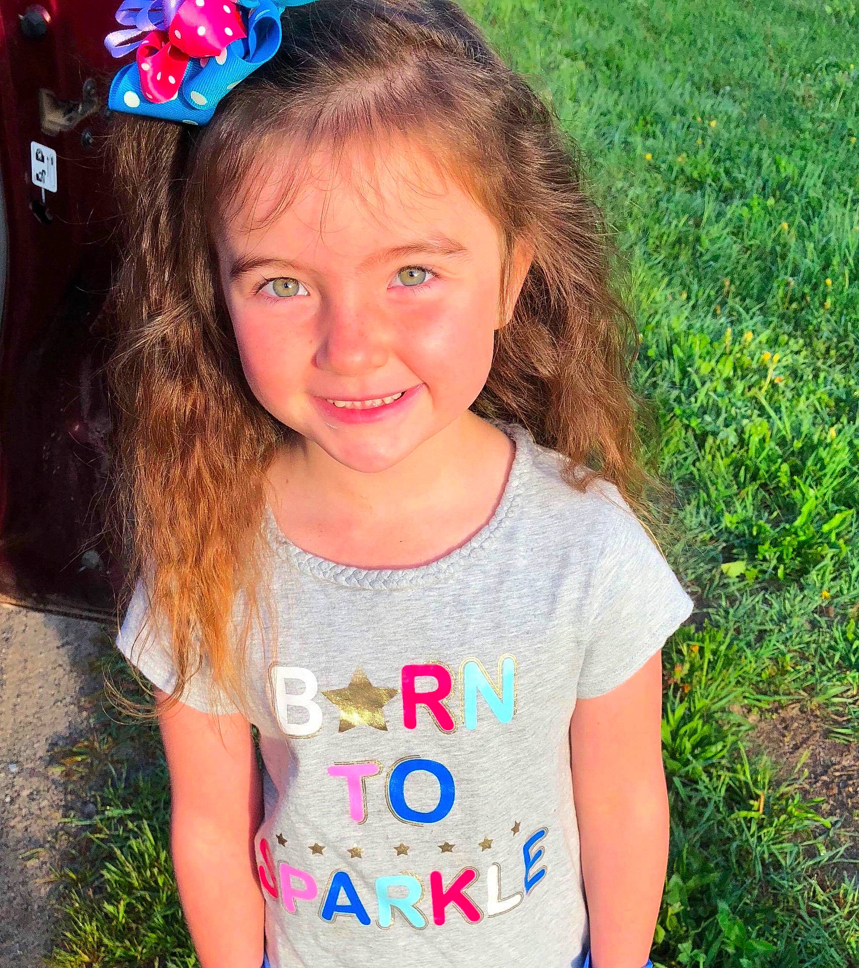 Ava is registered to the contest to win money with this photo: brown_hair, cheek, child, child_model, day, eye, facial_expression, fun, girl, grass, hairstyle, happiness, head, joy, long_hair, person, pink, shoulder, skin, smile