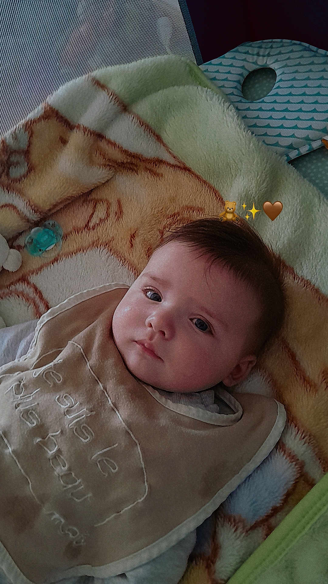 élyo a rejoint le concours — aidez-le/la à gagner de superbes lots ! baby, blanket, bib, face, infant, child, soft_texture, embroidery, clothing, lying_down, indoor, portrait, cute, young_child, warm_colors, head, expression, comfort, resting, closeup