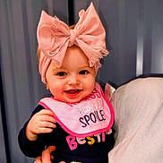 Kensli joined the competition — help win amazing prizes! baby, child, smiling, pink_bow, bib, clothing, person, portrait, happy, hand, headwear, indoor, cute, young_child, apparel, face, infant, expression, cheerful, holding