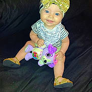 Kensli joined the competition — help win amazing prizes! baby, child, blue_eyes, golden_bow, striped_shirt, plush_toy, purple_toy, sitting, smiling, golden_sandals, headband, indoor, cute, portrait, happy, person, infant, toy, clothing, face