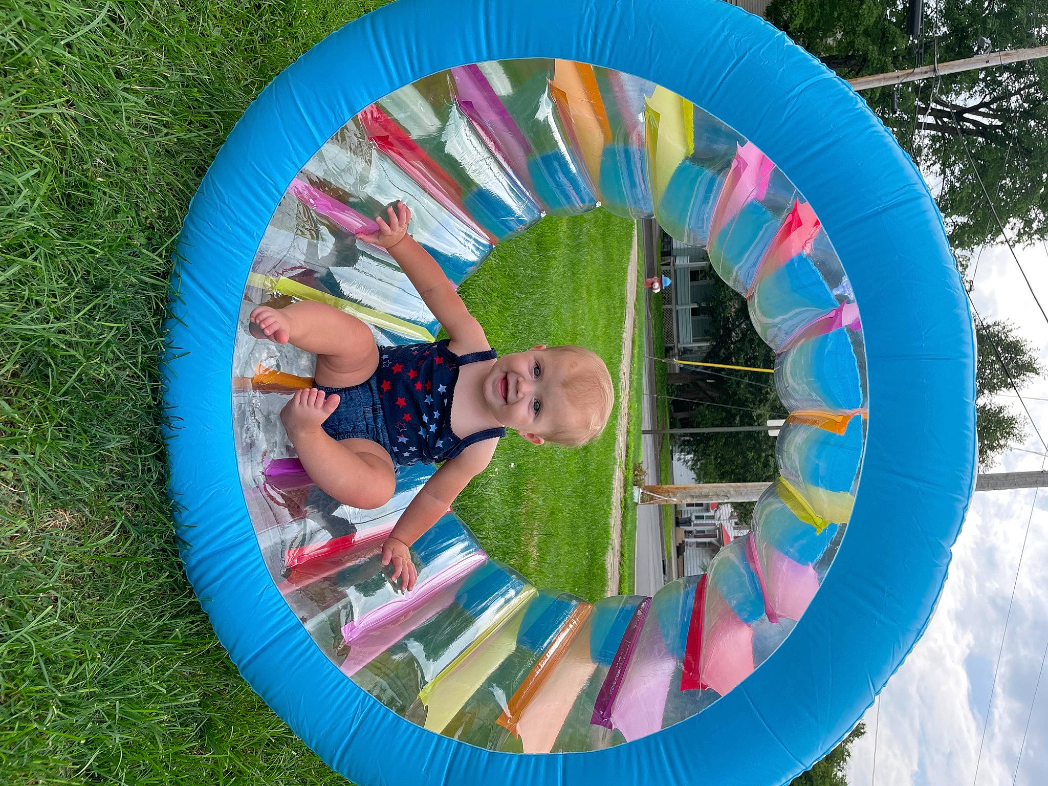 Alena is registered to the contest to win money with this photo: automotive_wheel_system, child, circle, cloud, electric_blue, fun, grass, inflatable, joy, leisure, people_in_nature, person, photograph, plant, play, pole, recreation, sky, summer, t_shirt