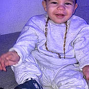 Kaëlan participe au concours pour gagner de l'argent avec cette photo : baby, blanket, candid, casual_clothing, cheeks, child, couch, face, footwear, gold_chain, happy, indoor, new_balance, portrait, purple_light, sitting, smile, sneakers, sweatshirt, toddler