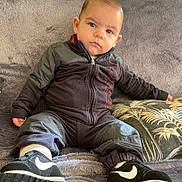 Kaëlan a rejoint le concours — aidez-le/la à gagner de superbes lots ! toddler, child, sitting, couch, blanket, sneakers, clothing, face, person, indoor, plush, portrait, footwear, expression, home, casual, jacket, pants, pillow, relaxed