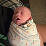 newborn, baby, sleeping, blanket, polka_dot, swaddled, infant, person, hand, indoor, cozy, carpet, laundry_basket, clothing, rest, peaceful, soft_light, toddler, family, portrait