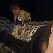 River is registered to the contest to win money with this photo: child, baby, bed, blanket, dark, indoor, person, sleeping, crawling, pajamas, pattern, family, cozy, portrait, home, infant, adult, face, clothing, rest