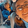 child, woman, car, car_seat, blue_jacket, glasses, earrings, smile, seatbelt, interior, happy, portrait, people, seat, casual, transportation, young_child, person, travel, family