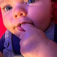 Legend is registered to the contest to win money with this photo: apparel, baby, blue_eyes, button, child, close_up, clothing, cute, expression, face, fingers, hand, infant, person, pink_background, portrait, skin, soft_lighting, sucking, young
