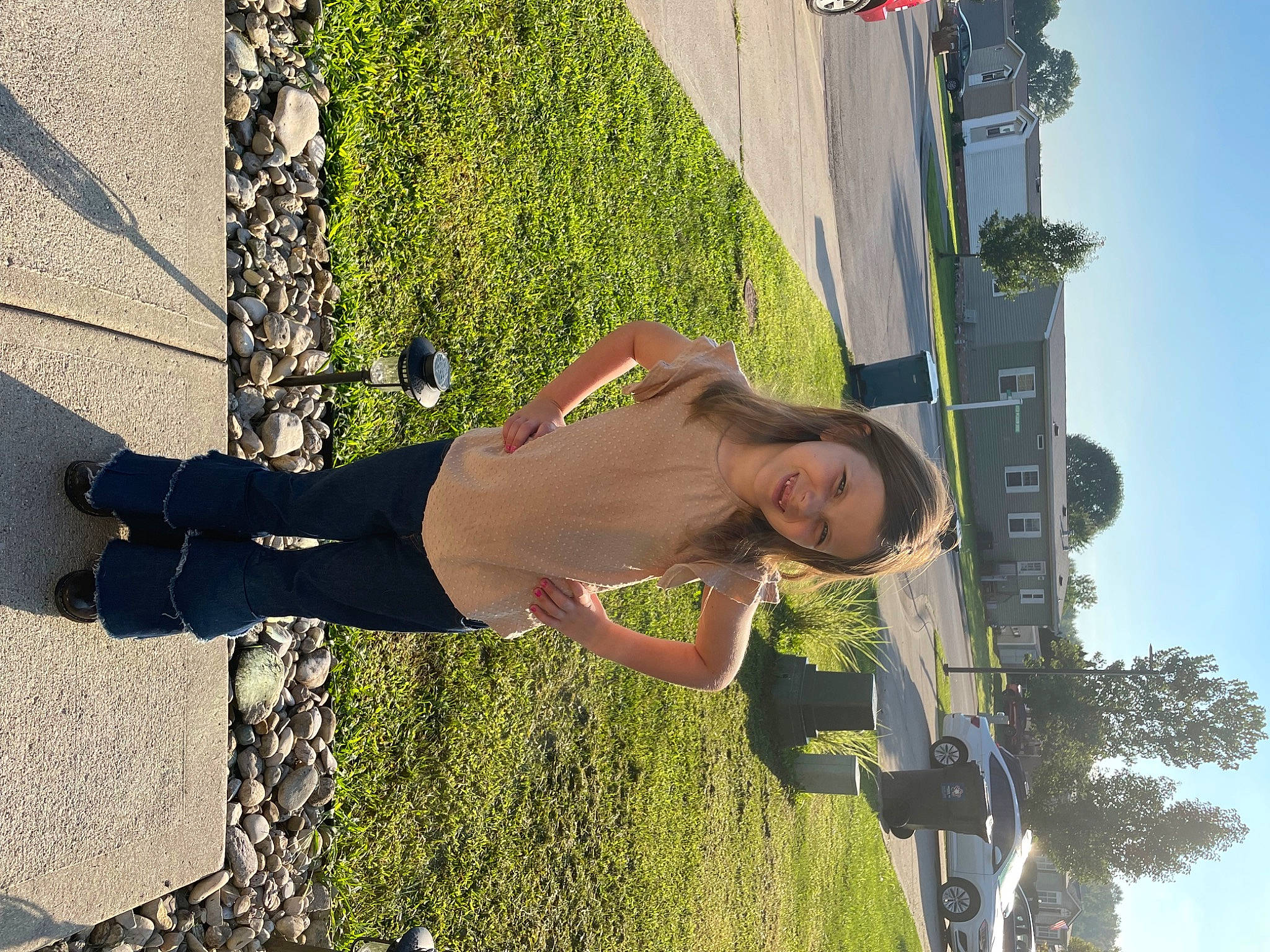 Renae is registered to the contest to win money with this photo: asphalt, eyewear, flag, fun, grass, green, human_leg, joy, leisure, people_in_nature, person, plant, pole, road_surface, shadow, shrub, sidewalk, sky, smile, thigh