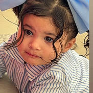 Donaima participe au concours pour gagner de l'argent avec cette photo : big_eyes, blue_bow, button, child, clothing, curly_hair, cute, expression, face, hair, indoor, light, mobile_screen, person, portrait, social_media, story, striped_shirt, toddler, young_child