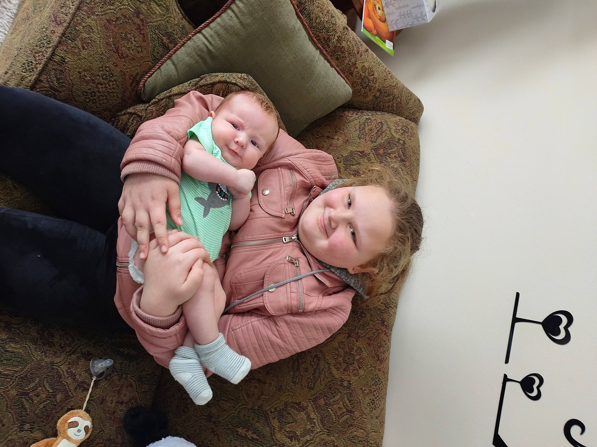 Rose-marie is registered to the contest to win money with this photo: arm, baby, baby_toddler_clothing, child, comfort, couch, flooring, foot, gesture, happy, head, human_leg, joy, leg, linens, people, person, sitting, thigh, thumb