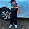 Axl James is registered to the contest to win money with this photo: black_clothing, car, casual, chain, child, confident, cool_pose, fashion, grass, outdoor, portrait, reflection, short_hair, smile, sunglasses, toddler, vehicle, wheel, white_sneakers, young_child