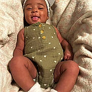 Ailyn is registered to the contest to win money with this photo: baby, infant, smiling, headband, green_outfit, white_socks, blanket, cozy, cute, portrait, happy, child, soft_texture, indoors, closeup, resting, small_person, adorable, warm, comfort