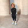 Yanis is registered to the contest to win money with this photo: child, boy, smiling, hoodie, tracksuit, sneakers, casual, standing, concrete, shadow, hands_in_pockets, indoor, sporty, fashion, happy, portrait, full_body, minimalist, clothing, young