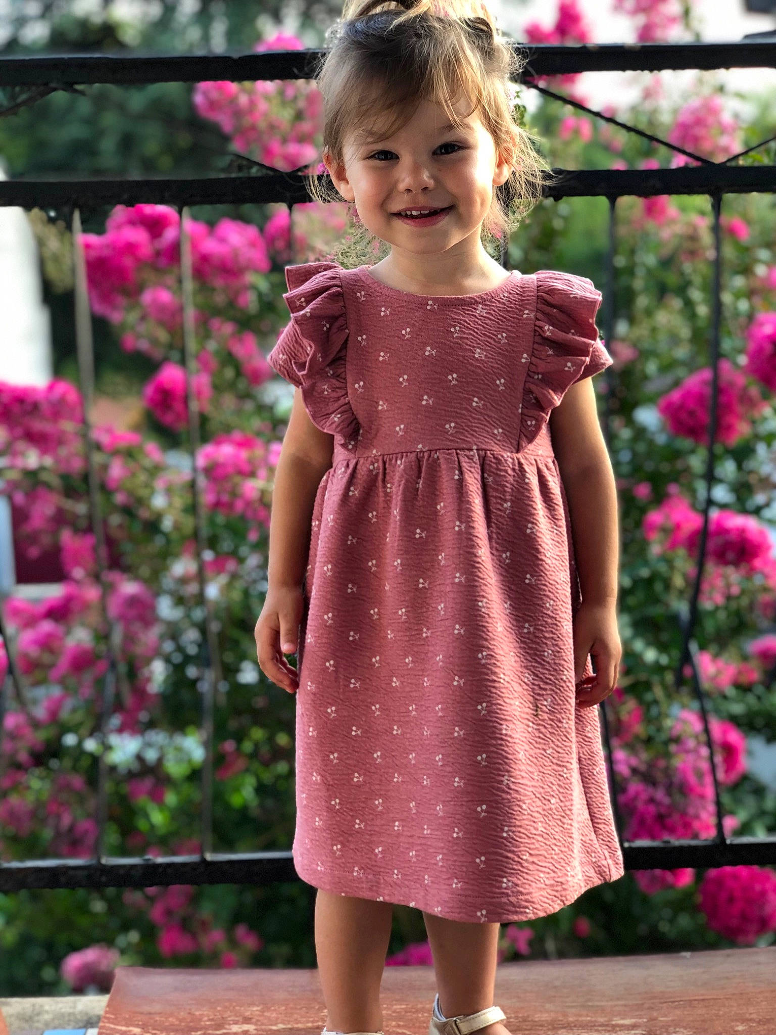 Louise a rejoint le concours — aidez-le/la à gagner de superbes lots ! baby_toddler_clothing, botany, child, day_dress, dress, flower, grass, happy, joy, leaf, magenta, one_piece_garment, person, petal, pink, plant, shoulder, sleeve, smile, standing