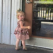 Willa is registered to the contest to win money with this photo: toddler, child, floral_dress, blonde_hair, sandals, door, reflection, curious, outdoor, concrete_floor, metal_wall, handle, portrait, standing, young_child, summer_clothing, cute, innocent, casual, daylight