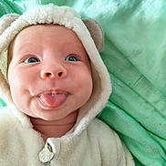 Lucian participe au concours pour gagner de l'argent avec cette photo : baby, infant, tongue_out, hoodie, soft, blanket, cute, face, expression, smile, blue_eyes, close_up, child, wearing_clothes, warm, indoor, portrait, baby_clothing, funny_face, playful