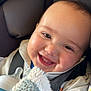 Michael is registered to the contest to win money with this photo: baby, smiling, face, infant, car_seat, blanket, bottle, child, cute, happy, clothing, seatbelt, closeup, indoors, person, head, skin, eyes, mouth, cheeks