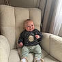Vinnie is registered to the contest to win money with this photo: baby, armchair, smile, socks, sweatshirt, pants, indoor, curtains, light, face, child, plush_furniture, happy, cozy, seated, cute, infant, furniture, portrait, soft_light