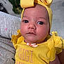 Arabella joined the competition — help win amazing prizes! baby, infant, yellow_clothing, headband, bow, face, eyes, person, child, cute, portrait, closeup, holding, soft_lighting, expression, indoors, fabric, pink, gray, background_blur