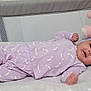 baby, infant, purple_outfit, headband, bow, blanket, star_pattern, teddy_bear, pink_toy, crib, mesh_sides, soft_toys, sleepwear, lying_down, cute, child, indoor, portrait, adorable, resting