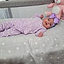 baby, infant, pajamas, headband, bow, crib, blanket, star_pattern, plush_toy, pink_bunny, soft_toys, lying_down, indoors, cute, child, sleeping_area, bedtime, comfort, smiling, person