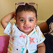 Riaan joined the competition — help win amazing prizes! baby, child, smiling, sitting, indoor, clothing, pink_chair, sunglasses, star_pattern, cute, portrait, happy, person, infant, short_hair, casual, playful, expression, light_background, hand_up