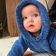 Nino participe au concours pour gagner de l'argent avec cette photo : baby, infant, child, blue_hoodie, knit_sweater, big_eyes, curious, crawling, play_mat, smile, portrait, indoors, floor, wooden_panel, toy_shelf, soft_light, skin, cute, hood, expression
