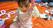 Ayla joined the competition — help win amazing prizes! bunny_ears, child, colorful, curly_hair, cute, decorations, easter_egg, face, festive, happy, indoor, orange_tablecloth, party, person, pink_boots, playful, seated, smiling, toddler, toy