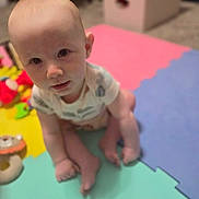 Isaiah joined the competition — help win amazing prizes! baby, child, infant, sitting, portrait, face, eyes, smile, curious, indoor, playroom, foam_mat, colorful, toy, clothing, onesie, barefoot, storage_box, home, photography