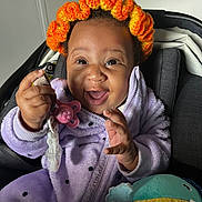 Jahïlys a rejoint le concours — aidez-le/la à gagner de superbes lots ! baby, child, smiling, pacifier, toy, headband, orange, purple, polka_dot, jacket, stroller, happy, infant, clothing, indoor, cute, person, face, hand, seated