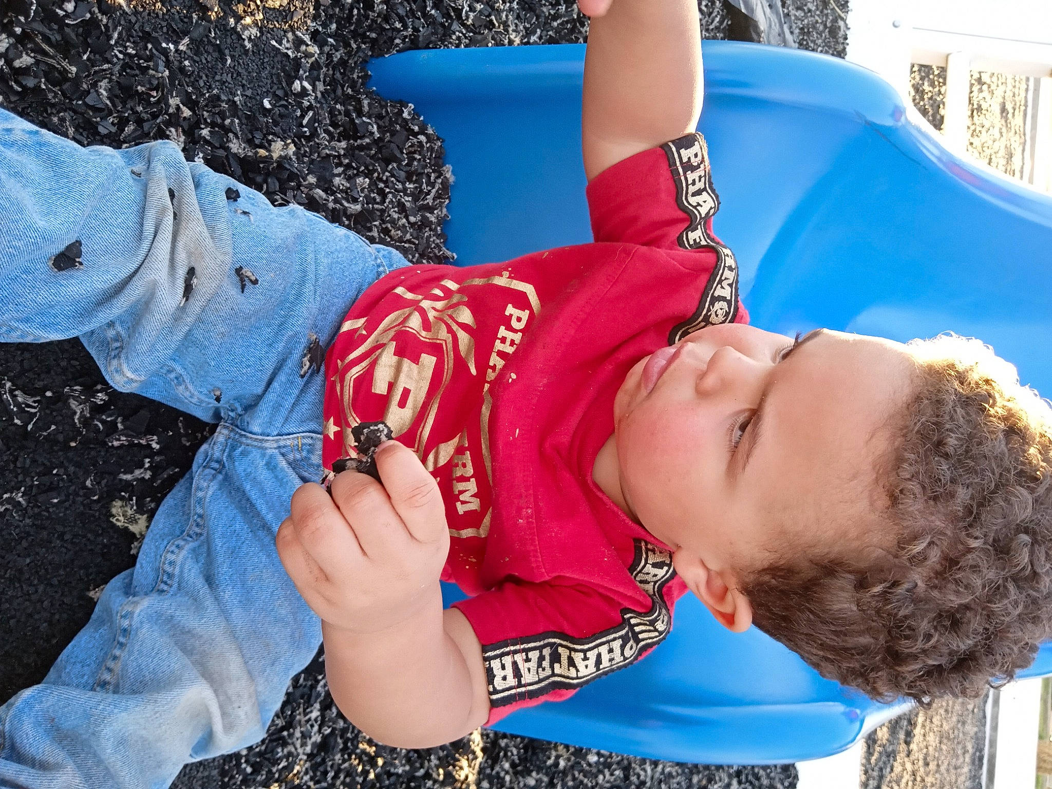 Keenan is registered to the contest to win money with this photo: arm, child, clothing, denim, electric_blue, eyewear, fun, grass, happy, human_leg, leisure, person, personal_protective_equipment, play, recreation, sitting, street_fashion, thigh, toddler, tree